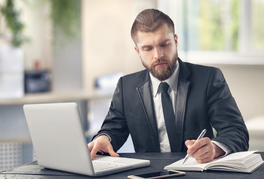 Young serious bearded man in blue shirt working on desktop | How to Get Pre-Qualified Leads on Autopilot | qualifying prospects