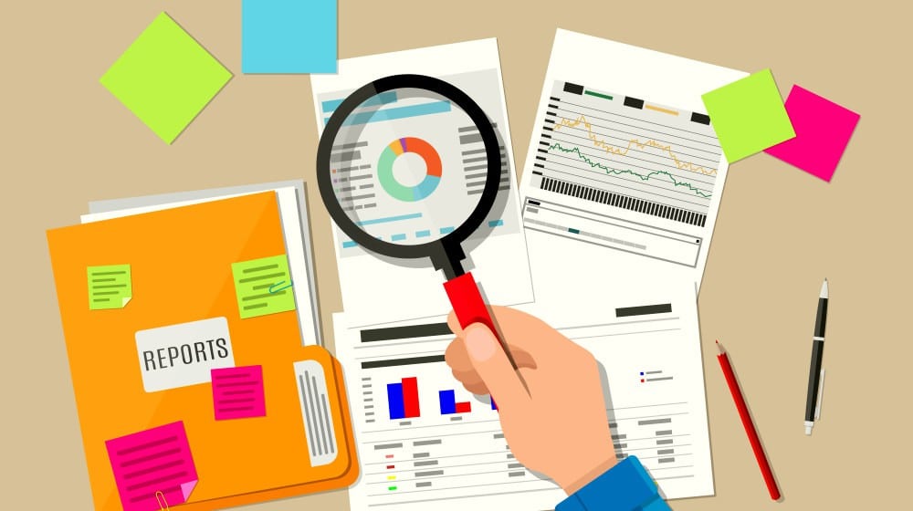 Alt text: Hand with magnifying glass, analysis of financial report | Why Is An Audit Trail Important in Bookkeeping? | what is audit trail | Featured