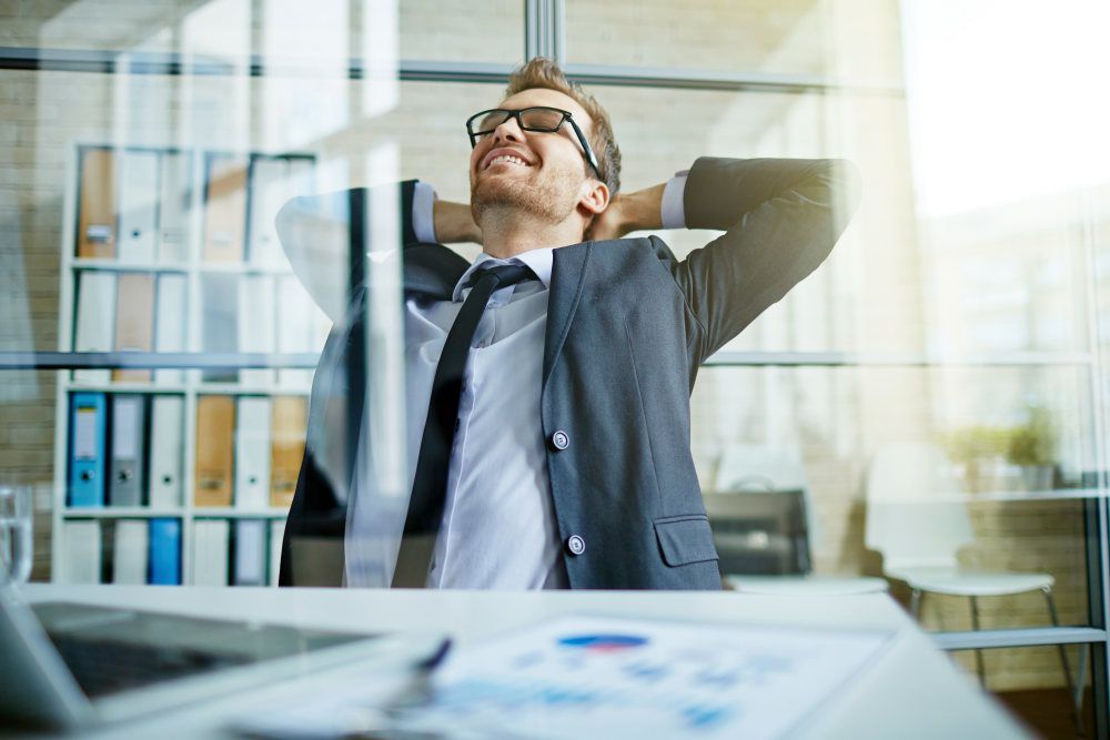 Happy businessman sitting with hands behind head | Outstanding Time Management Strategies For Bookkeepers | time management techniques