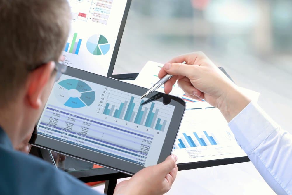 Business colleagues working and analyzing financial figures on a digital tablet | How To Measure Financial Performance Effectively | measure performance