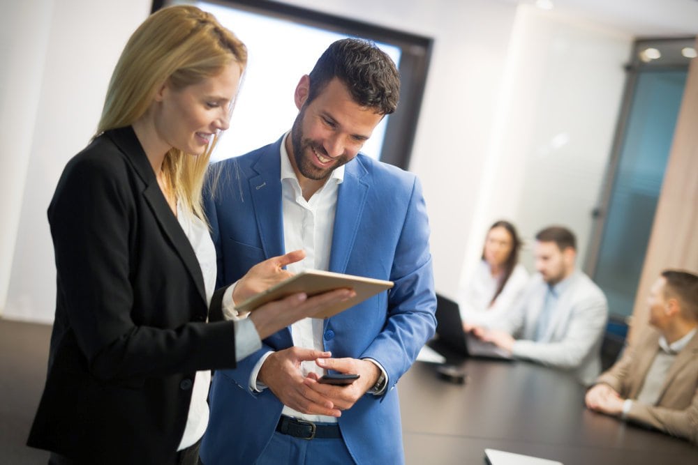 Businesspeople discussing while using digital tablet in office | Ways To Go Green With Your Accounting & Bookkeeping Practice | green accounting | ecosystem services