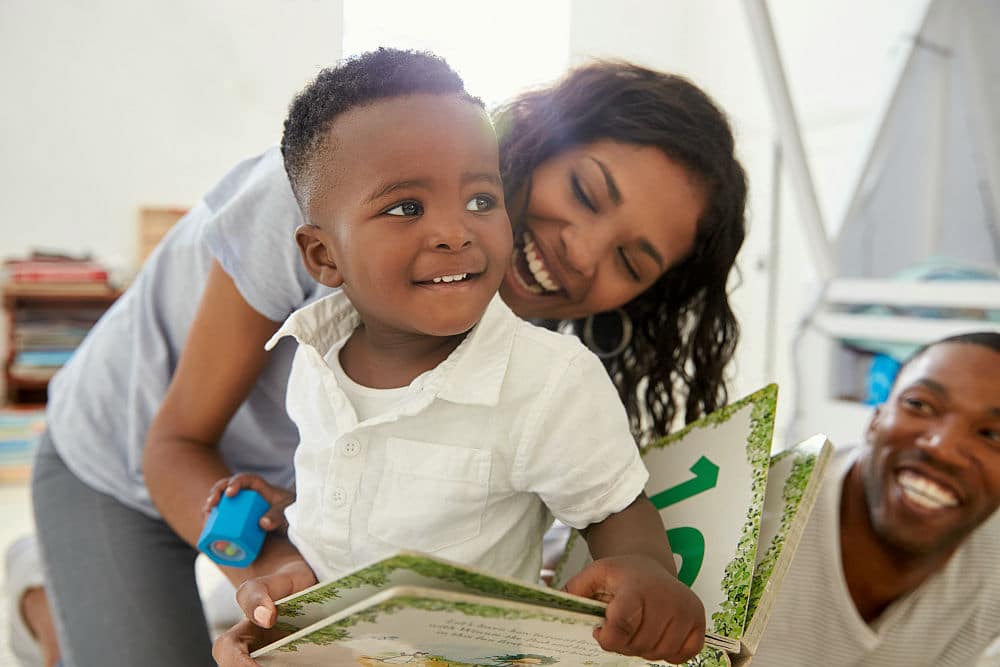 Family With Young Children Reading Book In Playroom Together | How To Set A Schedule For A Perfect Work From Home Routine | set schedule | work from home set your own hours