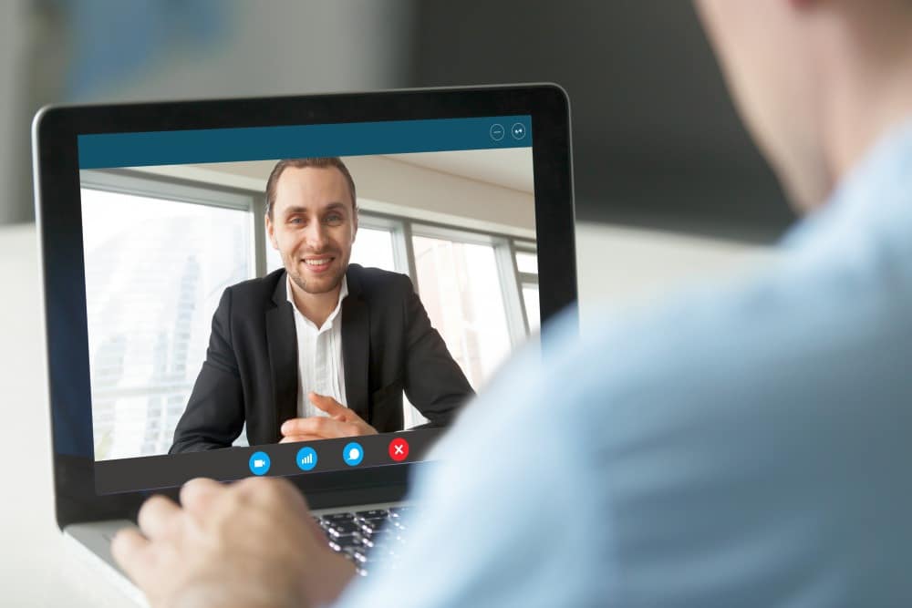 Friendly businessman smiling from laptop screen, | How To Manage A High Performing Remote Team: Effective Ways | team communication