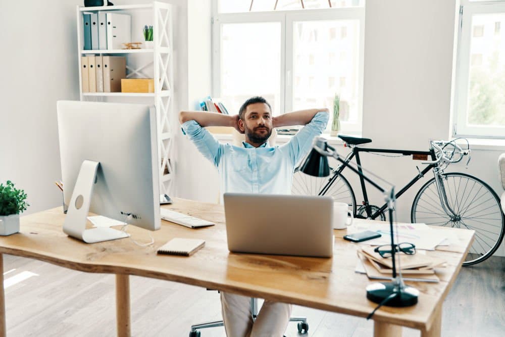 Relaxed middle age man in smart casual wear keeping hands behind head | Practical Ways To Stay In Shape While Working From Home | work from home tips