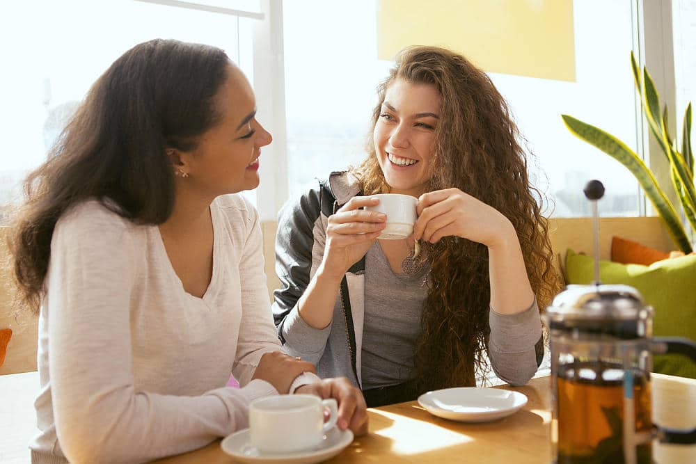 Cheerful girlfriends spending time together at the cafe talking and laughing | Practical Ways To Practice Self Care As A Solopreneur | self care ideas | self care for entrepreneurs