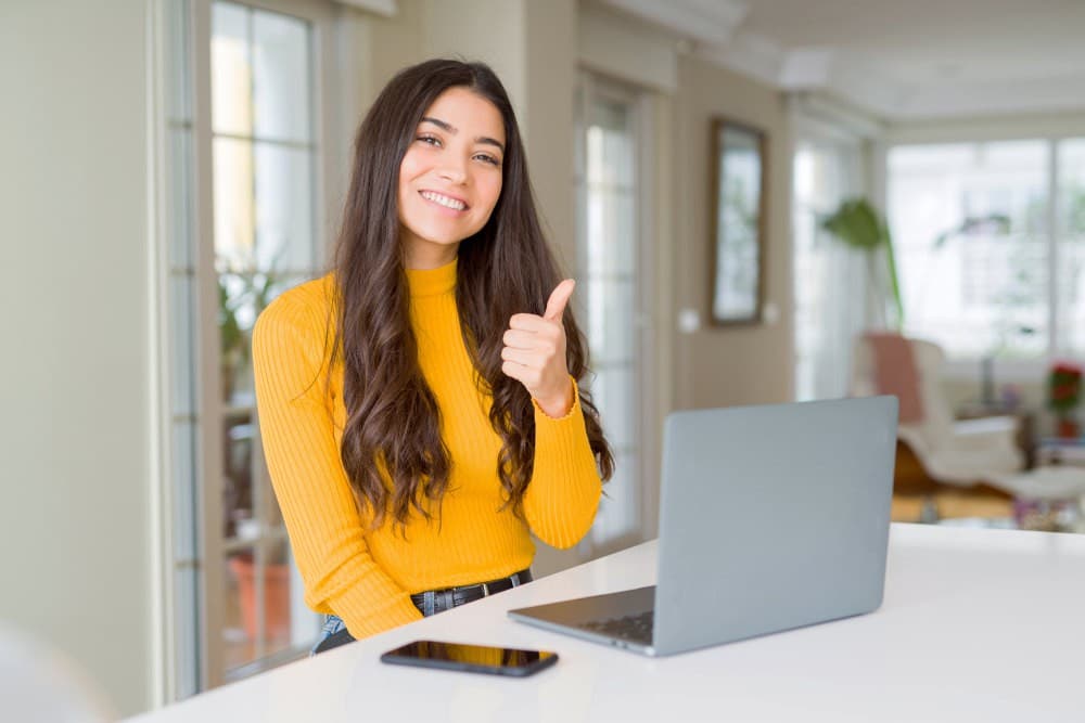 Young woman using computer laptop doing happy thumbs up gesture with hand | Practical Ways To Stay In Shape While Working From Home | working from home tips