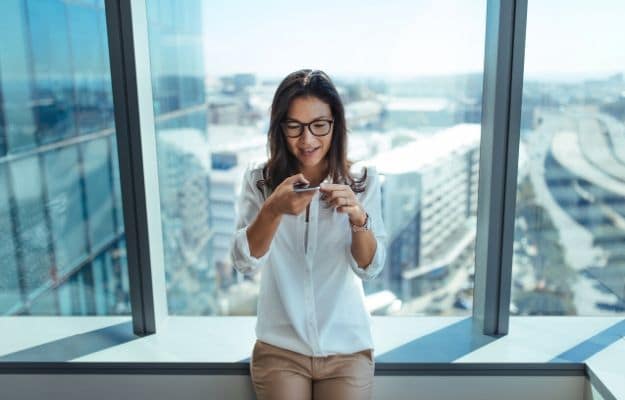 a woman is using voice chat on the phone by the window ca