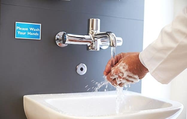 a man in suit washing his hands under water ca