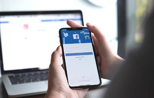 Woman hand holding iPhone X to use facebook with new login screen ss