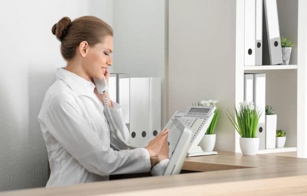 Young female receptionist talking on the phone in hospital ss