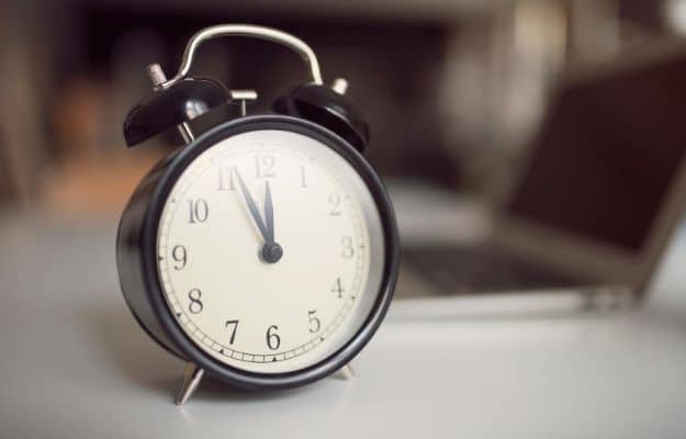 A close up of a clock standing on the table ca