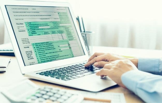 Accountants are filling online tax information using laptops | Filing on Paper | Avoid These 11 Tax Mistakes When Filing