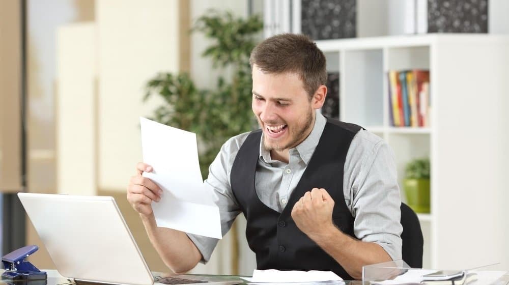 a man feeling excited while reading tax paper in office ca