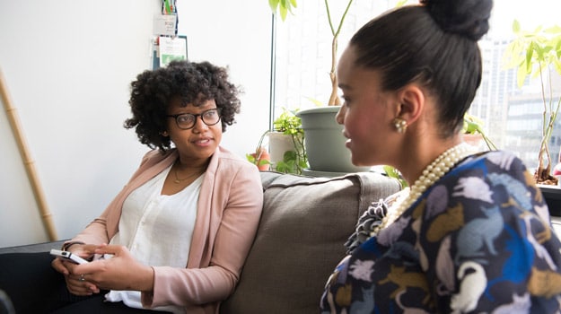 two black elegant women talk on sofa us