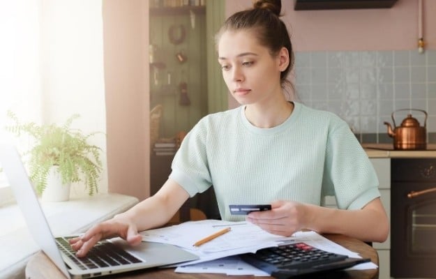 woman holding card and typing on computer | Residing in Multiple States | How To File Taxes If You ve Lived In Two States
