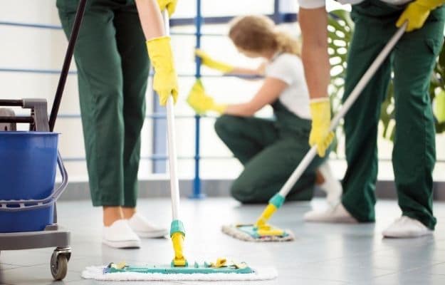 three people wearing yellow gloves are cleaning the floor and window ca