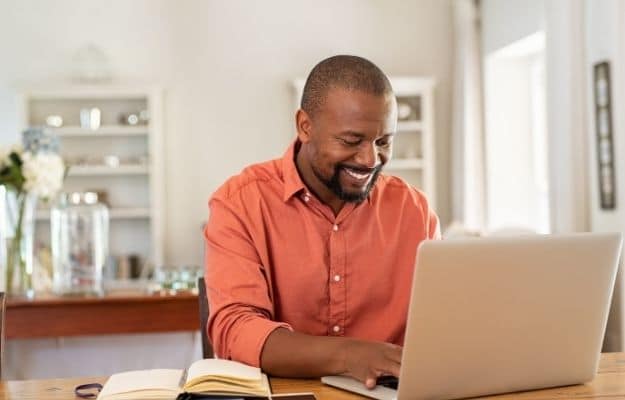 Smiling man using laptop at home in living room ss