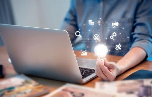 a man holding a light bulb a laptop and many icon around ca