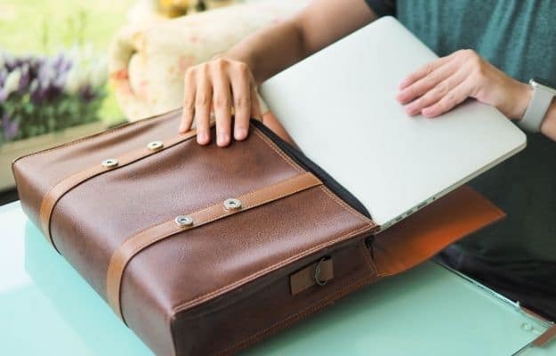 businessman hand putting laptop into the leather bag ss