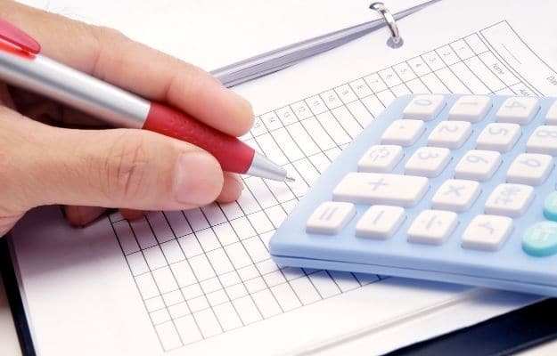 someone holding a pen, a calculator and a sheet on the table - ca| 8 Common Misconceptions About Bookkeeping | Bookkeepers are All Good at Math